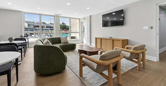 A living room with a green chair and a television on the wall.