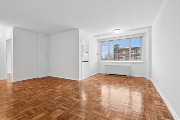 A room with wooden flooring and a window overlooking a building.