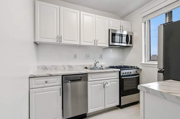A kitchen with white cabinets and appliances.
