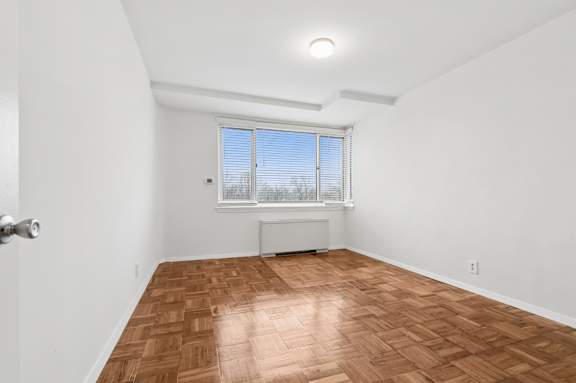 A room with a wooden floor and a window with blinds.