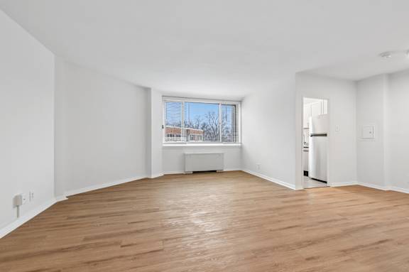 A large empty room with wooden floors and white walls.