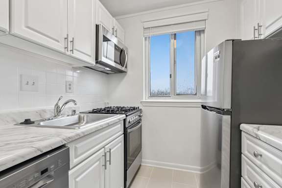 A kitchen with white cabinets and appliances.