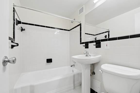 A white bathroom with a tub, sink, and mirror.