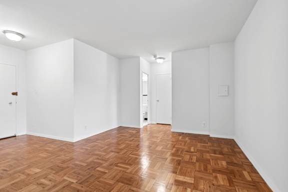 One bedroom living space with wooden flooring and white walls.