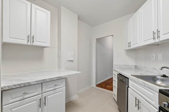 A kitchen with white cabinets and a marble countertop.