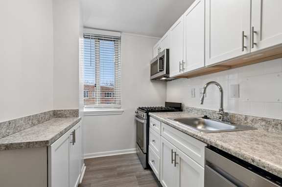 A kitchen with white cabinets and a granite countertop.