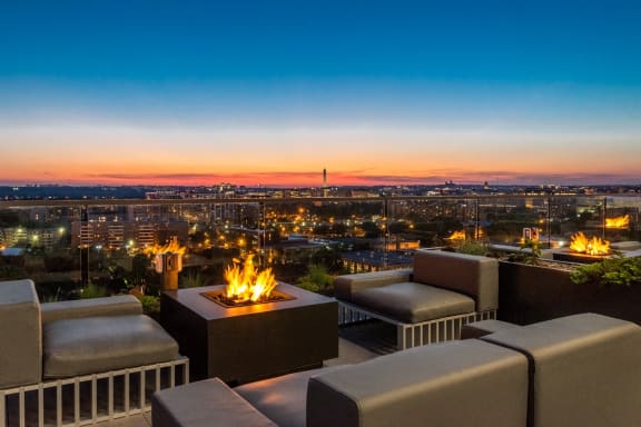 an outdoor patio with a fire pit overlooking the city at dusk