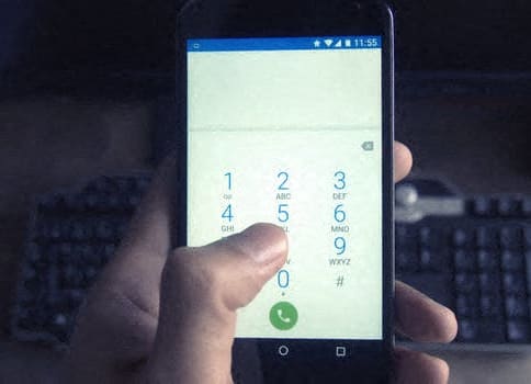 a person holding a cell phone with a keyboard in the background