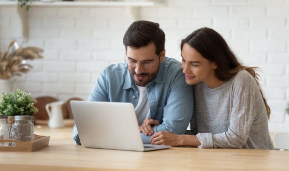 a man and woman looking at a laptop computer