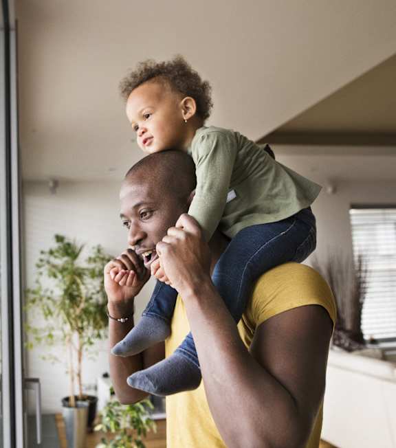 a father holding his child on his shoulders in a living room