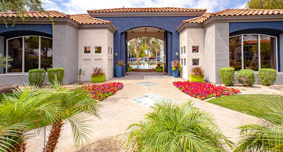 A house with a blue roof and white walls with a garden in front.