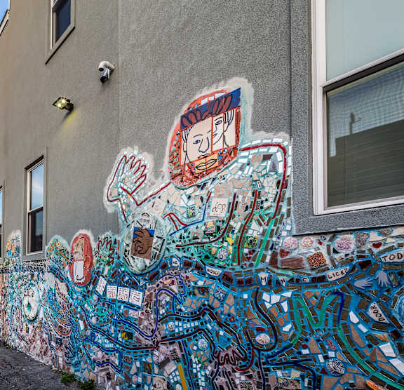 A wall covered in graffiti art with a blue sky in the background.