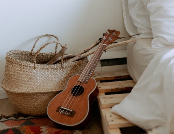 a guitar next to a bed and a basket