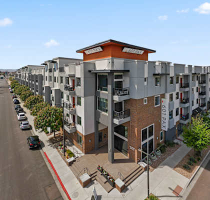 a row of apartment buildings with a parking lot in the foreground