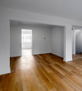 the living room and dining room of a house with wooden floors and white walls