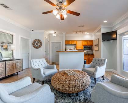 A living room with a white couch, a wicker coffee table, and a ceiling fan.
