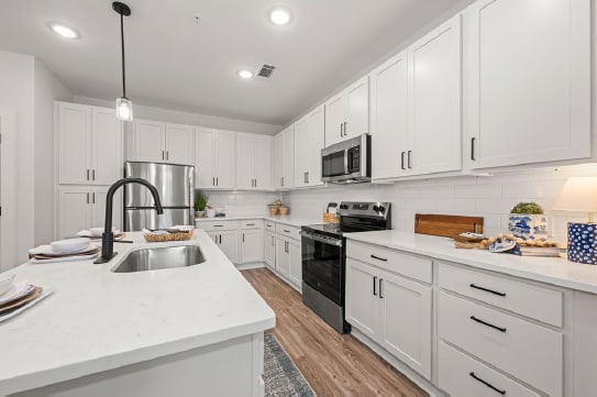 A modern kitchen with white cabinets and a wooden cutting board.