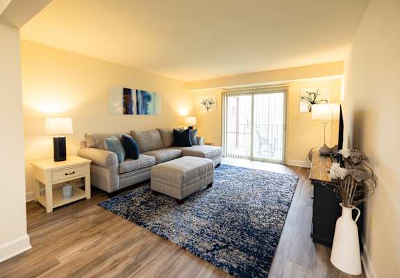 A living room with a grey couch and a blue rug.at Rockdale Gardens Apartments & Townhomes, Baltimore