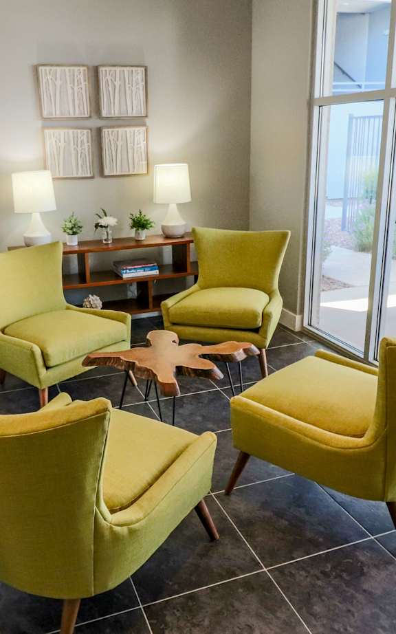 A living room with a blue couch and orange pillows.
