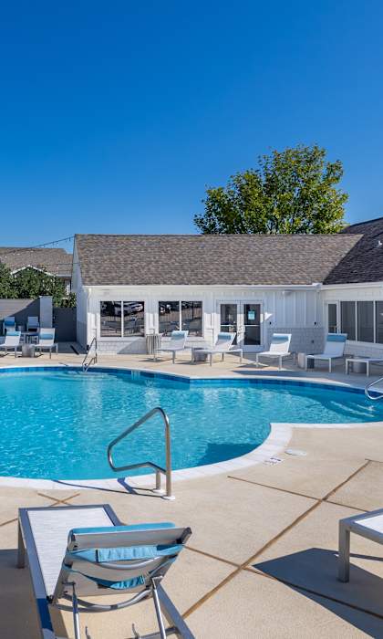 A pool with chairs and a table in the foreground.