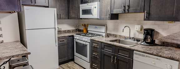 an updated kitchen with white appliances and dark cabinets