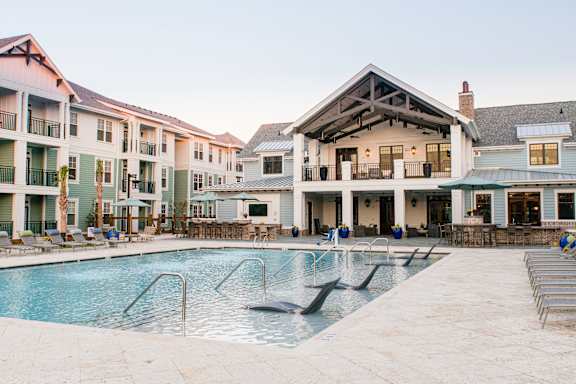 A large swimming pool in front of a building with a patio area at Wharf 7 Apartments, Charleston, SC