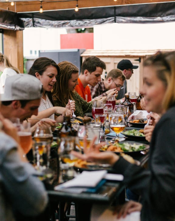 a group of people sitting around a long table eating food