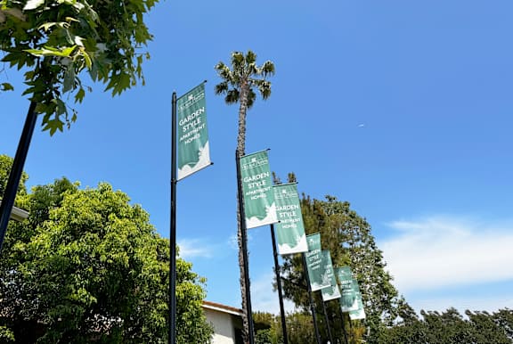 A row of green banners with white text hang from a black pole.