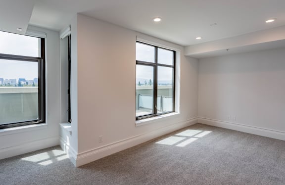 an empty living room with three windows and carpeting at Vendome Place, San Jose, 95110