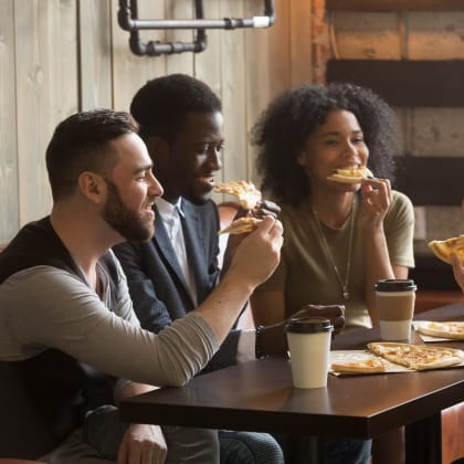 people eating pizza at a table in a restaurant