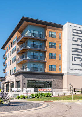 A street view of a building with the sign at The District at Deerfield Residences Apartments, Mason, OH, 45040