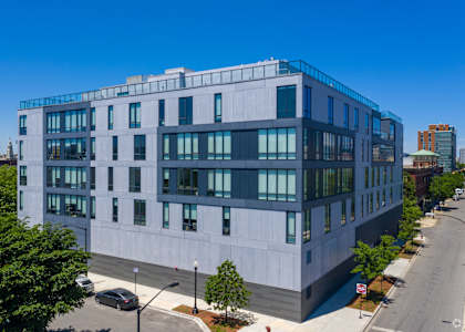A modern building with a flat roof and large windows is situated on a street corner.