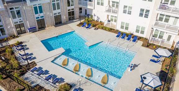 A large swimming pool surrounded by lounge chairs and umbrellas.