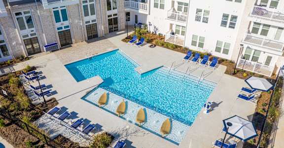 A large swimming pool surrounded by lounge chairs and umbrellas.