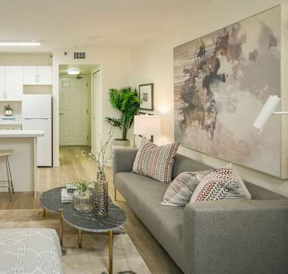 A modern living room with a kitchen in the background.