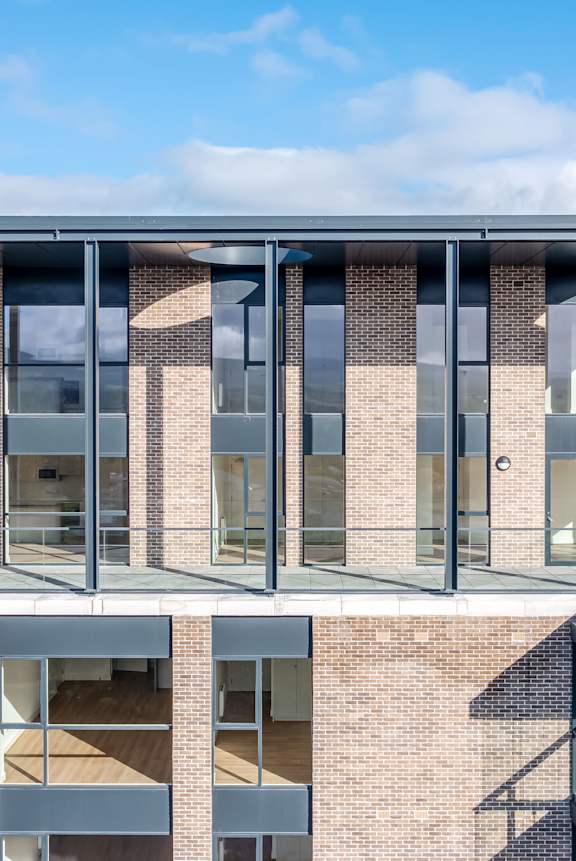 A modern building with a glass facade and a metal roof.