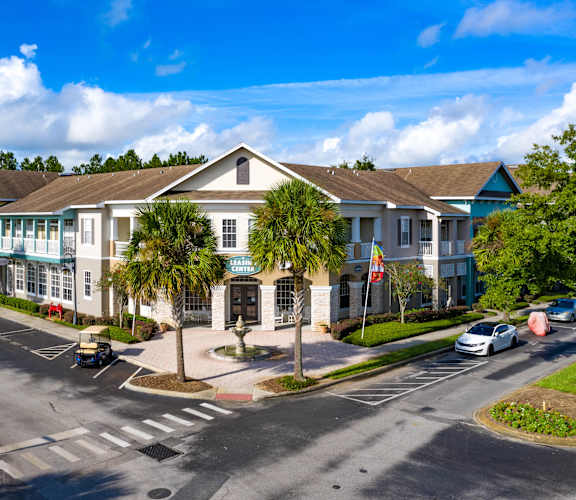 A sunny day at a residential complex with cars parked and driving.