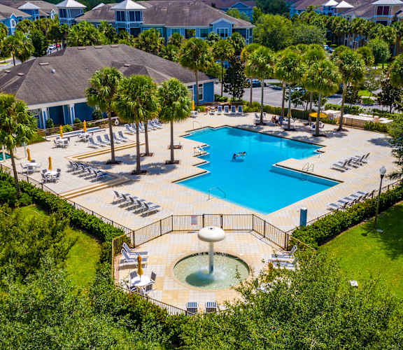 A large swimming pool surrounded by trees and a fountain.