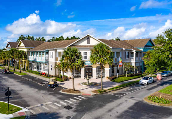 A sunny day at a residential complex with cars parked and driving.