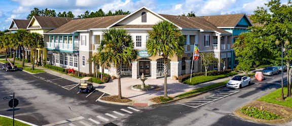 A sunny day at a residential complex with cars parked and driving.