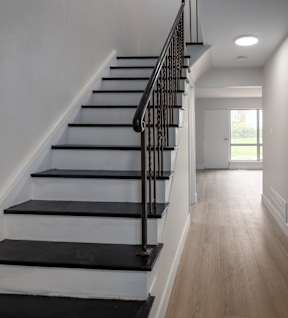 the view from the bottom of the stairs into the hallway of a house