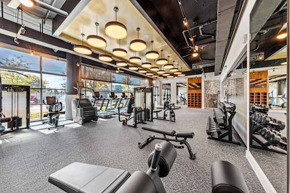 a gym with weights and cardio equipment on the floor and a view of a building  at South and Hollis, North Carolina