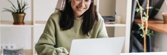 a woman sitting at a desk looking at a laptop computer