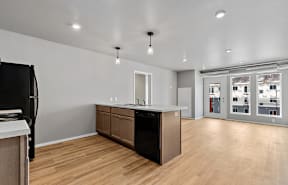 an open kitchen and living room with wood flooring and a large window