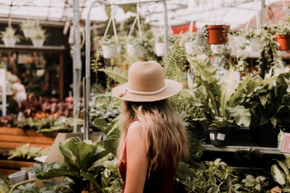 a woman in a straw hat standing in a greenhouse