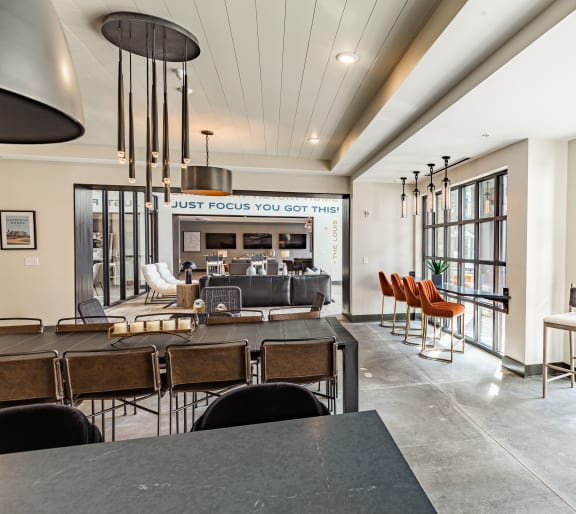a communal area with tables and chairs and large windows at The Louis Apartment Flats, Louisville, KY
