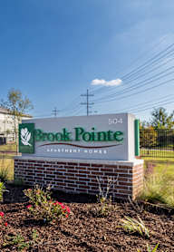 A sign for Brook Pointe Apartment Homes is in front of a building.
