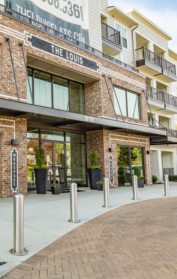 an exterior view of a building with glass doors and a sidewalk at The Louis Apartment Flats, Louisville, KY