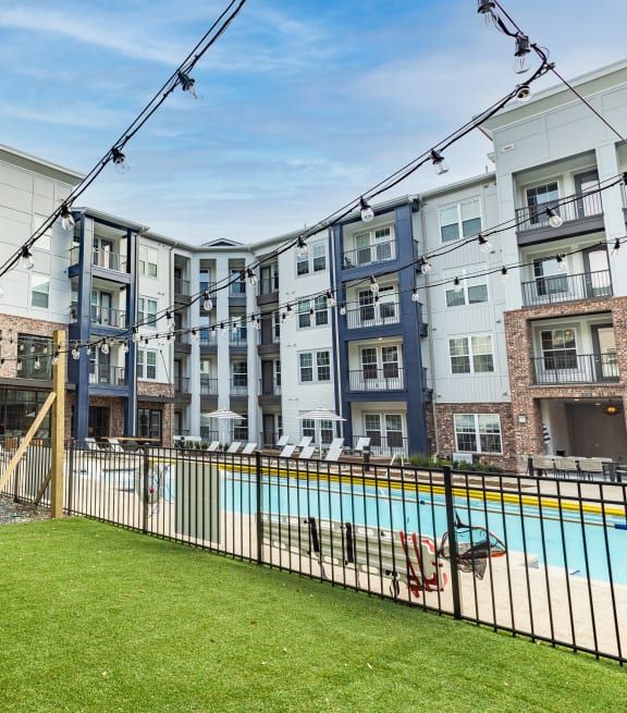 an apartment building with a swimming pool and a fenced in yard at The Louis Apartment Flats, Louisville, KY