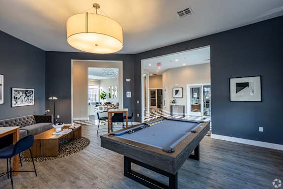 A pool table is in the middle of a room with a couch and a chair.